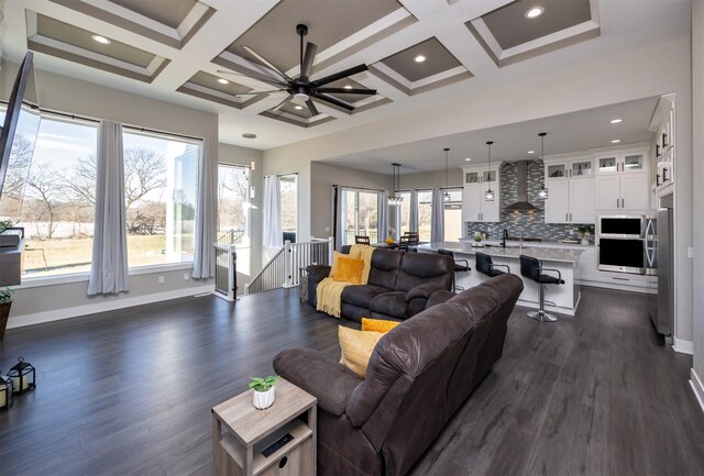 living room featuring ceiling fan, dark hardwood / wood-style flooring, beam ceiling, and coffered ceiling