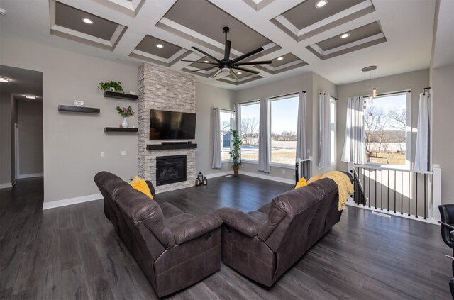 living room featuring plenty of natural light, a stone fireplace, and coffered ceiling