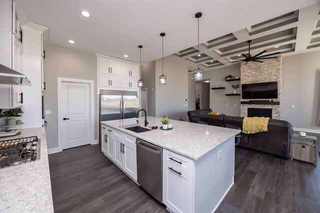 kitchen featuring white cabinetry, coffered ceiling, a stone fireplace, appliances with stainless steel finishes, and sink