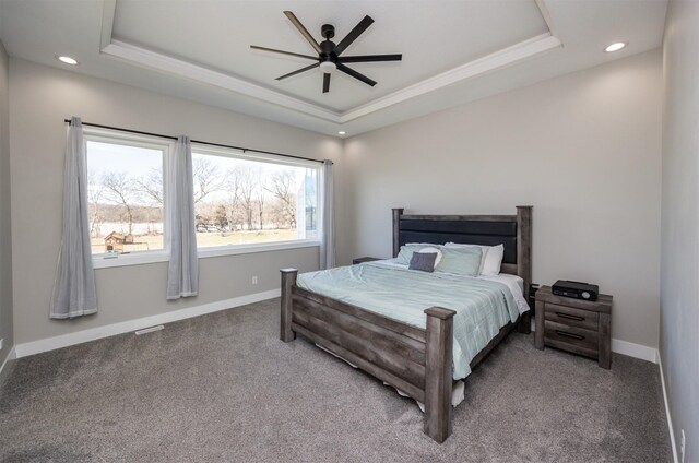 carpeted bedroom featuring ceiling fan and a tray ceiling