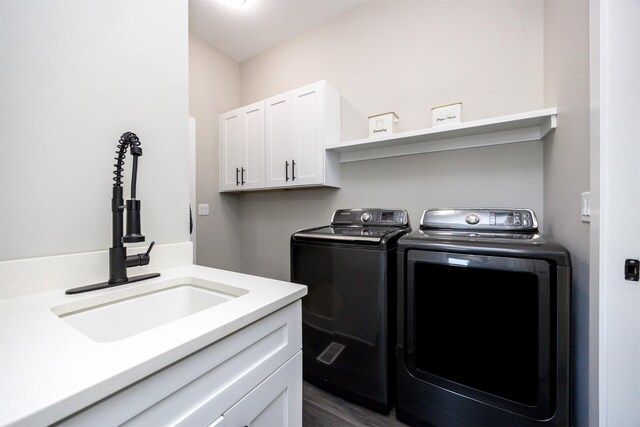 laundry room with dark wood-type flooring, cabinets, washer and clothes dryer, and sink