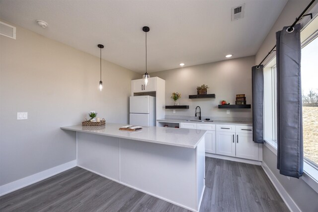 kitchen with decorative light fixtures, white cabinetry, white refrigerator, sink, and dark hardwood / wood-style floors