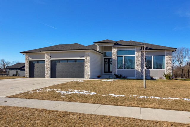 prairie-style home featuring a front yard and a garage