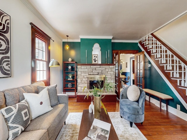 living room featuring ornamental molding, hardwood / wood-style floors, and a stone fireplace