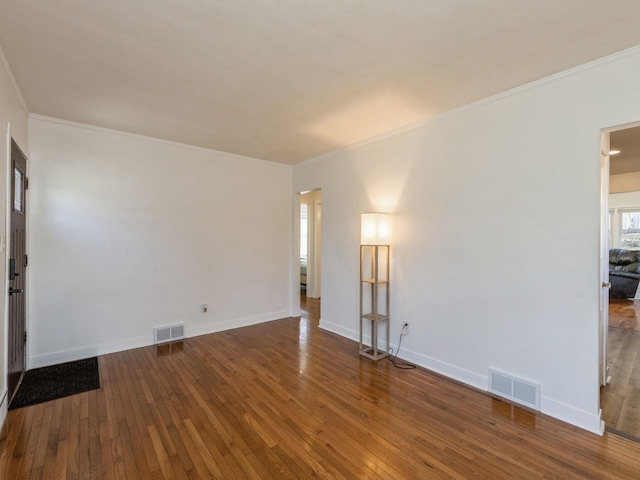 empty room with ornamental molding and hardwood / wood-style flooring