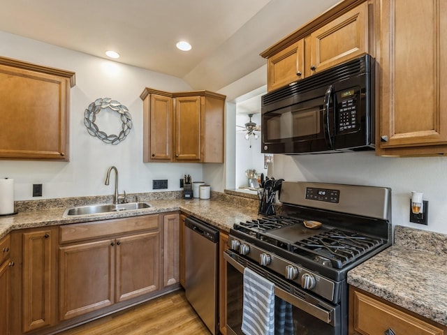 kitchen with ceiling fan, stone counters, sink, light wood-type flooring, and appliances with stainless steel finishes