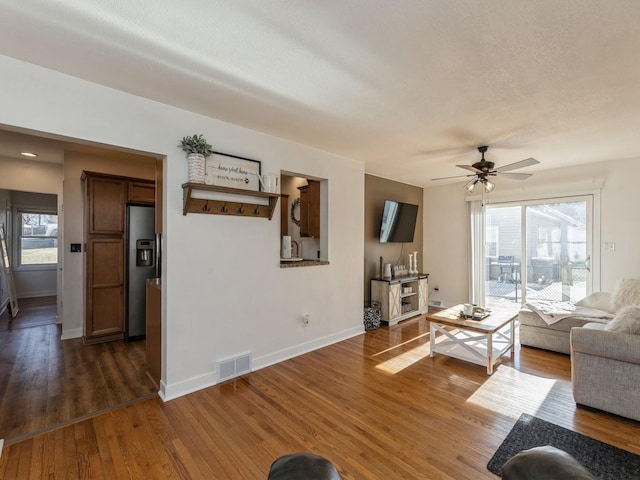 living room featuring ceiling fan, dark hardwood / wood-style flooring, and a textured ceiling