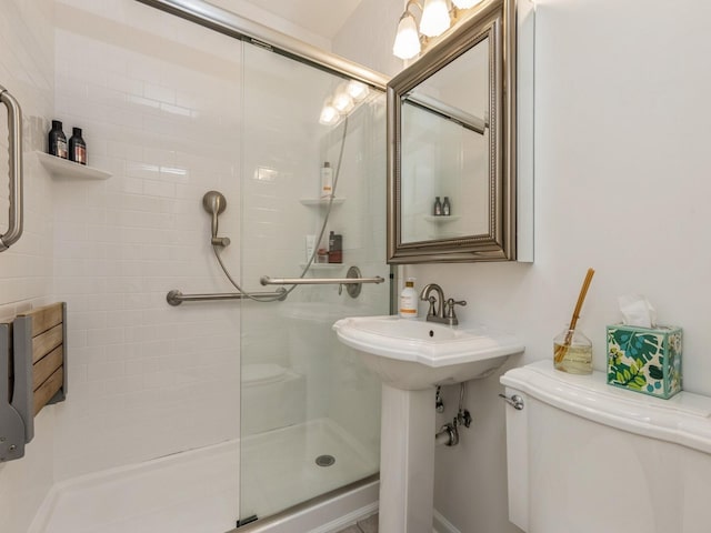 bathroom featuring toilet, sink, and a shower with door