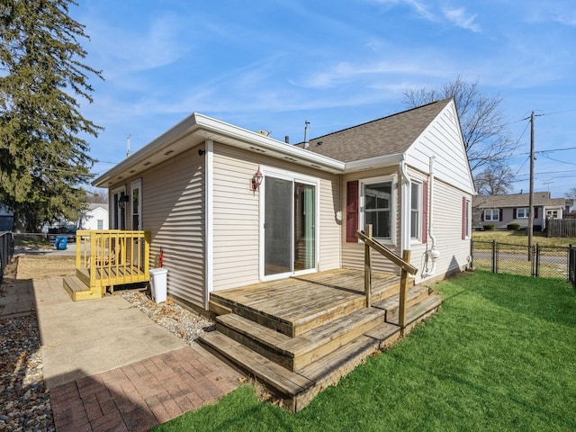 rear view of property featuring a wooden deck and a lawn