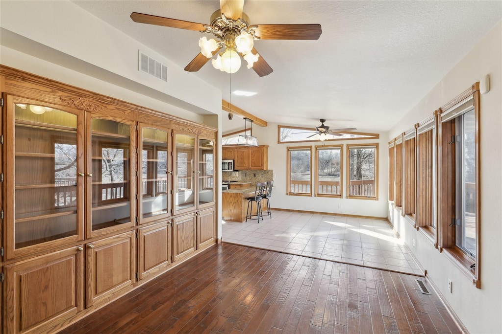 unfurnished sunroom featuring ceiling fan and lofted ceiling with beams