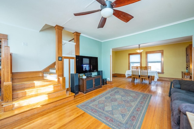 living room featuring ceiling fan, hardwood / wood-style floors, crown molding, and ornate columns