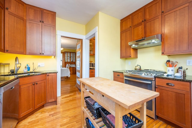 kitchen with light hardwood / wood-style floors, sink, stainless steel appliances, and dark stone countertops