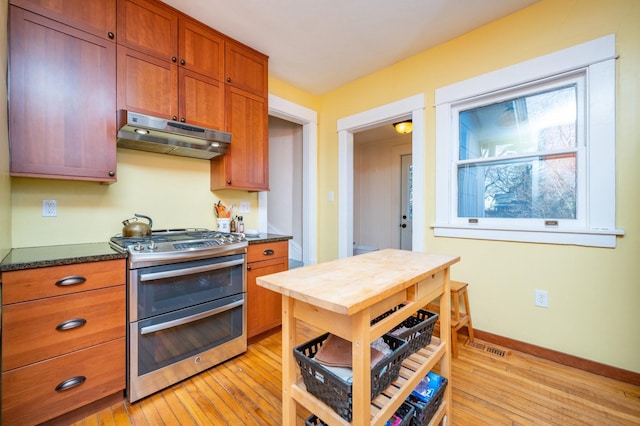 kitchen featuring light wood-type flooring, double oven range, and dark stone counters