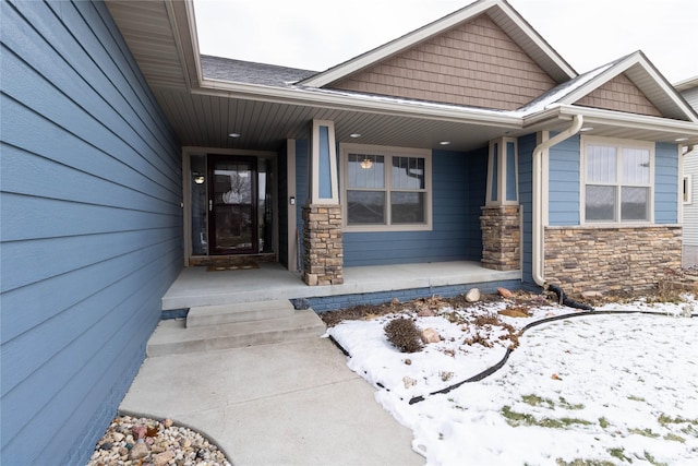 snow covered property entrance with covered porch