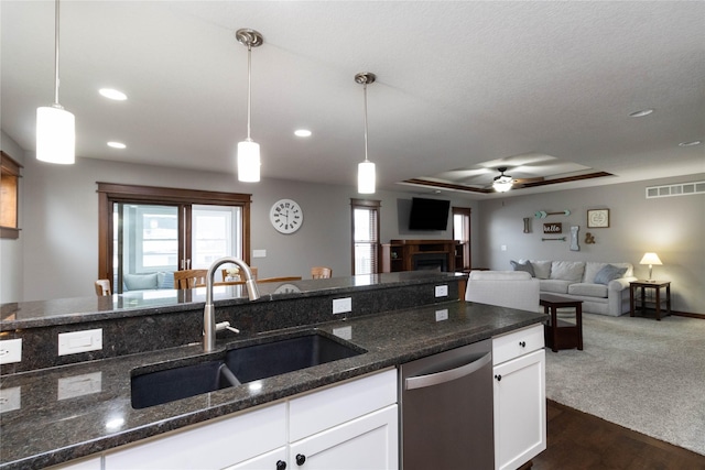 kitchen with white cabinets, dark stone countertops, sink, hanging light fixtures, and stainless steel dishwasher