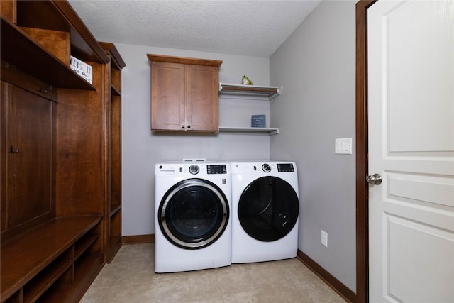 laundry room with cabinets, a textured ceiling, washer and clothes dryer, and light tile patterned flooring