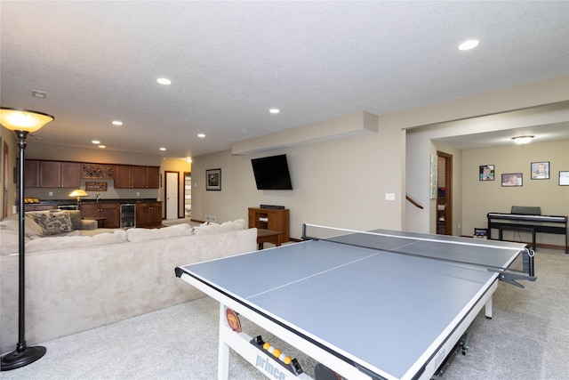 rec room featuring light carpet, a textured ceiling, and wine cooler