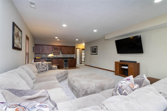 living room with light colored carpet, a textured ceiling, and beverage cooler