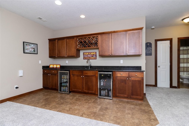 kitchen featuring light carpet, a textured ceiling, wine cooler, and sink