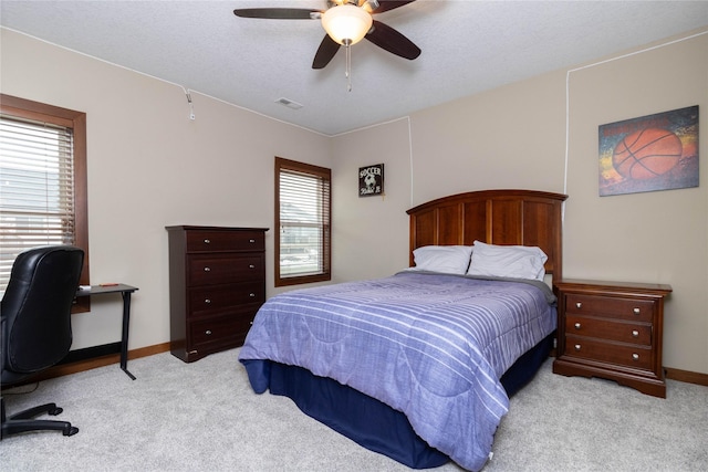 bedroom with ceiling fan, light colored carpet, and multiple windows