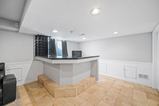 bar featuring a textured ceiling, wainscoting, visible vents, and recessed lighting