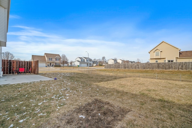 view of yard featuring a patio area, a fenced backyard, and a residential view