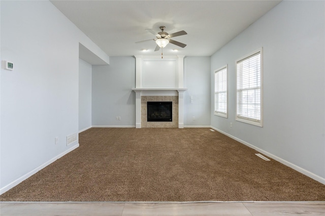 unfurnished living room featuring light carpet, ceiling fan, and a tiled fireplace