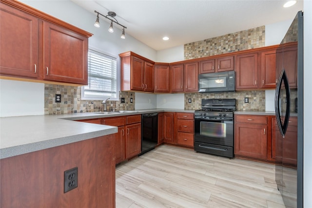 kitchen with sink, backsplash, light hardwood / wood-style flooring, and black appliances