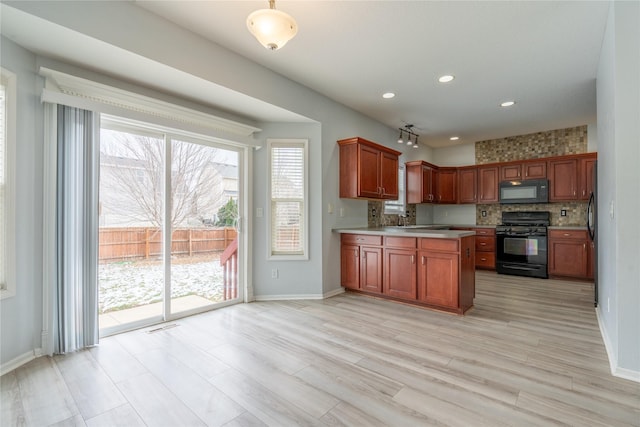 kitchen featuring decorative backsplash, light hardwood / wood-style floors, black appliances, and sink