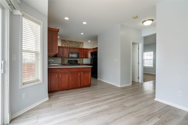 kitchen featuring sink, light hardwood / wood-style floors, tasteful backsplash, and black appliances