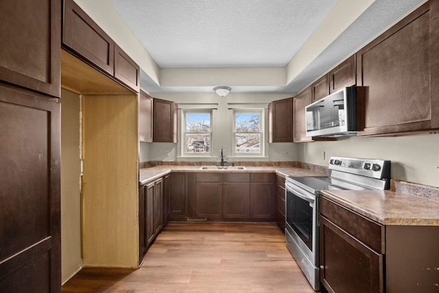 kitchen featuring sink, dark brown cabinetry, light hardwood / wood-style flooring, a textured ceiling, and stainless steel appliances