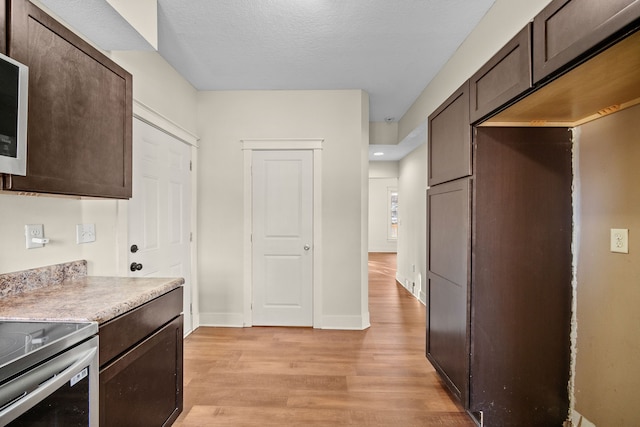 kitchen with a textured ceiling, light hardwood / wood-style flooring, and dark brown cabinets