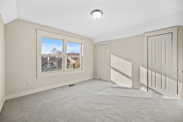 interior space with vaulted ceiling and light colored carpet