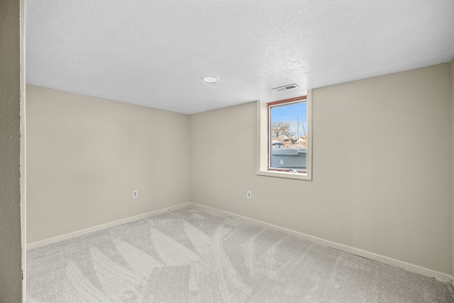 spare room featuring light carpet and a textured ceiling