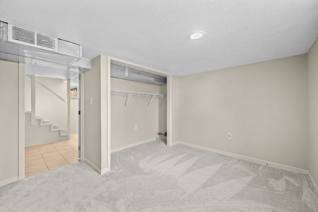 unfurnished bedroom with light carpet, a closet, and a textured ceiling