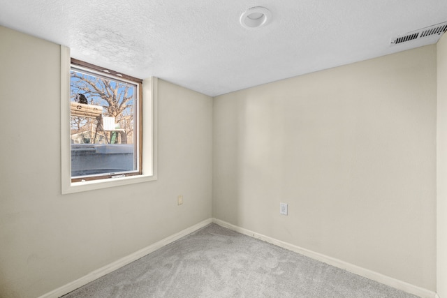 carpeted empty room with a textured ceiling