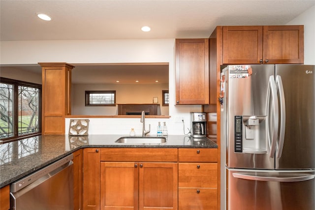 kitchen featuring decorative columns, appliances with stainless steel finishes, backsplash, dark stone countertops, and sink