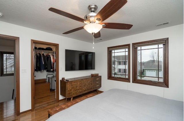 bedroom with a textured ceiling, ceiling fan, a closet, and hardwood / wood-style flooring