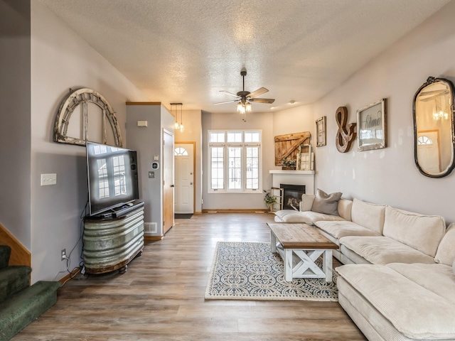 living room featuring ceiling fan, a textured ceiling, and hardwood / wood-style flooring