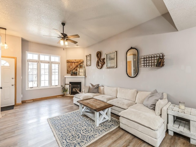 living room featuring ceiling fan, a textured ceiling, and light wood-type flooring