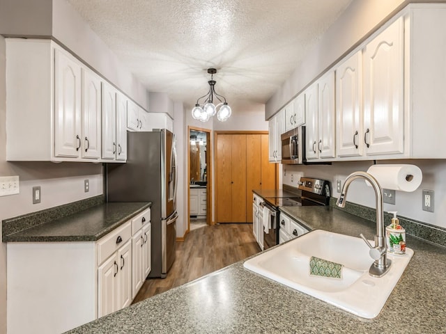 kitchen with decorative light fixtures, white cabinetry, sink, stainless steel appliances, and a textured ceiling