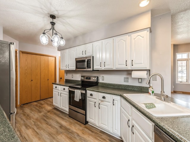 kitchen with white cabinetry, sink, hanging light fixtures, and appliances with stainless steel finishes