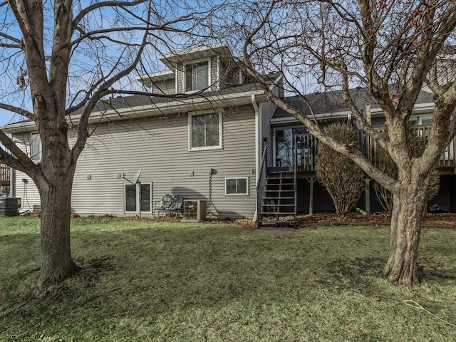 back of house with central AC unit and a yard