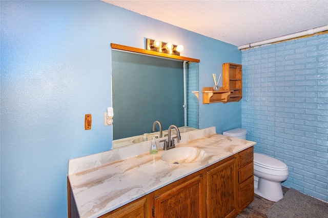 bathroom featuring a textured ceiling, toilet, and vanity