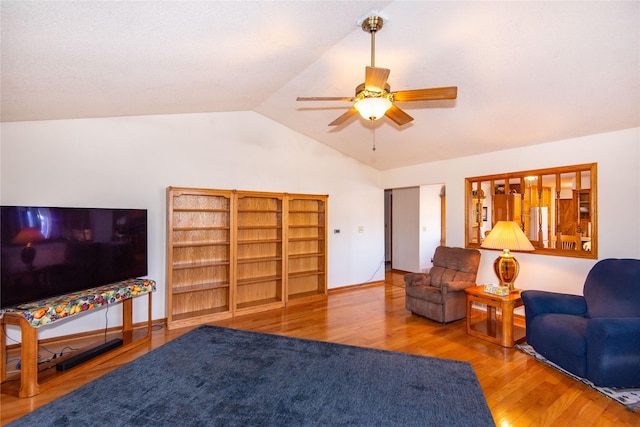 living room with ceiling fan, wood-type flooring, and vaulted ceiling