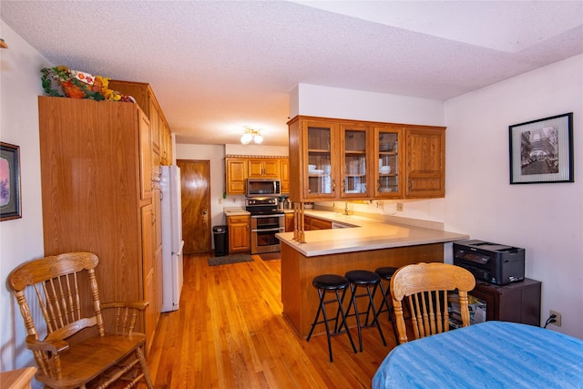 kitchen with a textured ceiling, stainless steel appliances, and kitchen peninsula