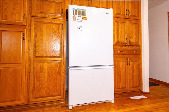 kitchen with a textured ceiling, white refrigerator, and light hardwood / wood-style flooring