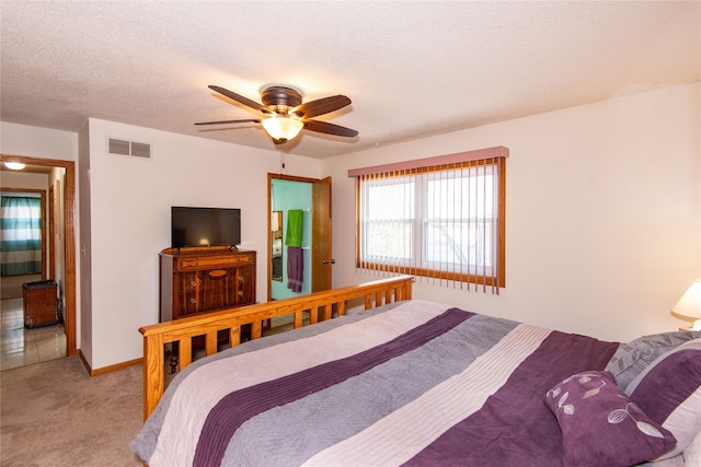 bedroom with ceiling fan, light colored carpet, and a textured ceiling