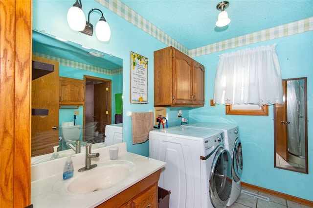 laundry area featuring a textured ceiling, light tile patterned floors, washer and clothes dryer, and sink