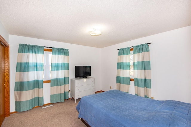 bedroom with light colored carpet and a textured ceiling